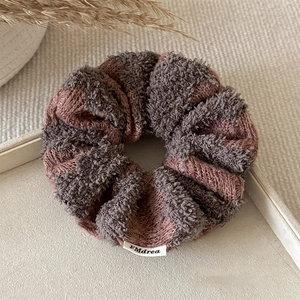 Close-up of soft knit scrunchie with plush texture and woven logo tag on tray