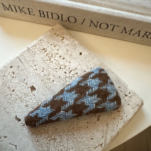 Gros plan sur une pince à cheveux triangulaire à motif pied-de-poule marron et bleu