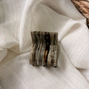 Close-up of small acetate hair claw clip with brown marble pattern on white linen fabric