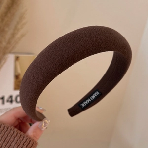 Detail of a brown handmade padded headband featuring a soft matte texture and interior label