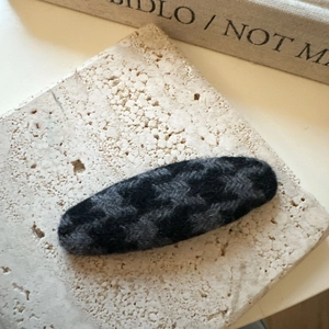 Détail d'une barrette rétro en tricot à motif pied-de-poule sur support en pierre