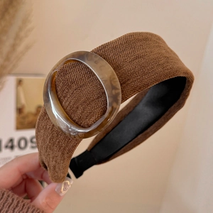 Close-up of brown knitted wide headband with amber resin leopard print ring buckle