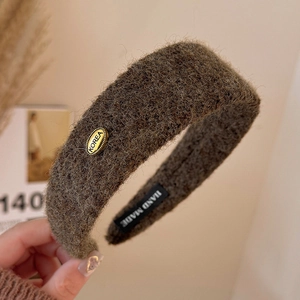 Detailed close-up of dark brown plush velvet headband with Korea metal tag and gold buckle