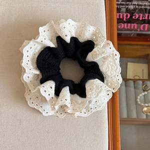 Detailed view of black knit scrunchie with white eyelet lace embroidery edges