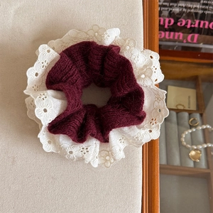 Close-up of dual-tone scrunchie featuring burgundy knit wool and white lace embroidery details