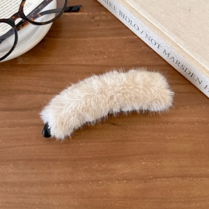Crèmefarbene Bananen-Haarklammer aus Kunstpelz für Winter-Pferdeschwänze auf Holztisch