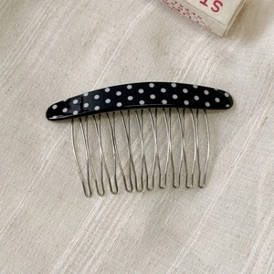 Detailed view of polka dot acetate hair comb with eleven wavy silver metal teeth