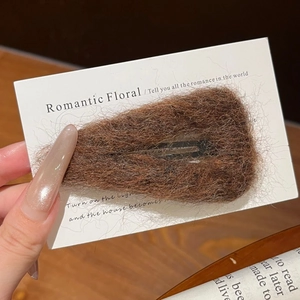Détail de la pince à cheveux triangle en peluche marron avec texture en laine bouclée