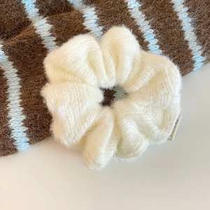 Nahaufnahme eines weichen weißen Strick-Scrunchies mit flauschiger Mohair-Struktur und Details