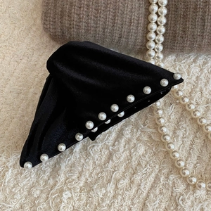 French vintage black velvet hair claw clip with elegant pearls on a warm background