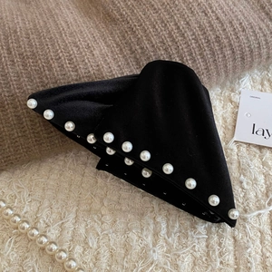Detail of elegant black velvet hair claw clip with neatly inlaid pearls on a soft fabric base