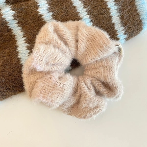Nahaufnahme von pfirsichfarbenem Strick-Scrunchie mit weicher Mohair-Textur-Details
