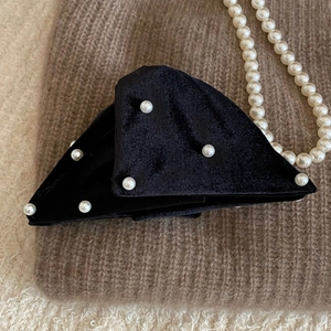 Detailed view of vintage black velvet hair claw clip with white pearls on knit background