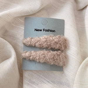 Detail of plush lamb wool triangular BB hair clips in warm brown on a display card