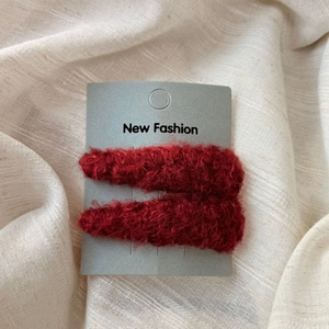 Close-up of two deep red plush triangle hair clips on display card with metal clip detail
