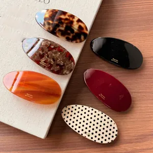 Macro shot of a 6-piece oval acetate barrette set with assorted marble patterns and textures
