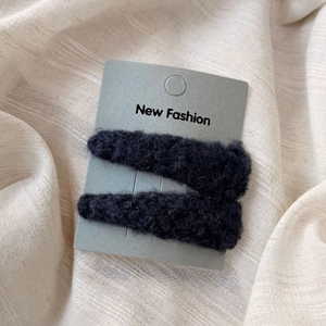Close-up of black plush lamb wool triangle hair clips on a New Fashion display card