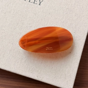 Detailed macro view of an oval amber texture barrette with Barrette la France gold lettering