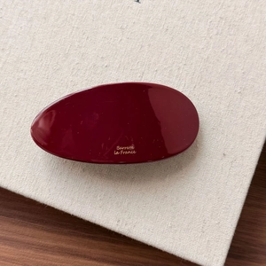 Close-up of a red oval marble resin hair clip with golden Barrette La France text engraving