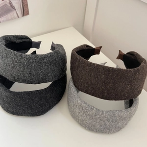 Serre-têtes larges en laine tricotée dans les tons gris et noir sur un bureau blanc