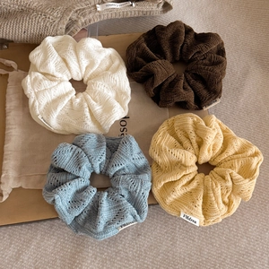 Set of four hollow knit scrunchies in cream, brown, blue, and yellow fabric texture