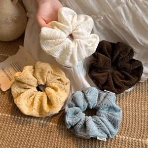 Set of four knitted scrunchies in cream, yellow, brown, and blue colors for women