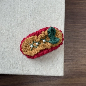 Detail of handmade knit hair clip with vintage red yarn and white faux pearl accents