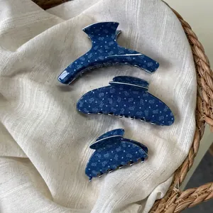 Set di tre pinze per capelli in acetato blu denim con motivi a cuore su lino beige