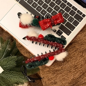 Drei Weihnachts-Haarspangen aus Wolle in Rot und Grün mit Schleifen auf einem Laptop
