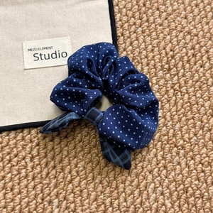 Navy blue polka dot scrunchie with checkered bow tie on rustic textured background