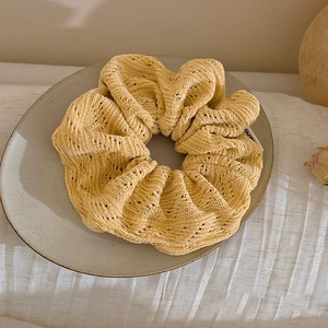 Detailed view of ginger yellow knitted scrunchie with crochet hollow pattern texture