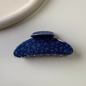 Dettaglio della molletta blu per capelli con texture denim e piccoli motivi a cuore