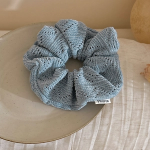 Close-up of light blue knitted scrunchie with soft wavy texture and FMdrea label