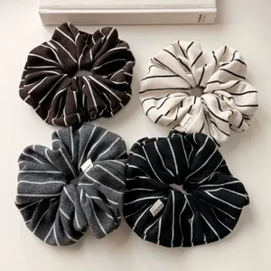 Close-up of four knitted striped scrunchies with Hand Made labels in neutral tones
