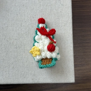 Detail of handcrafted crochet Christmas tree hair clip with red bow and star decorations