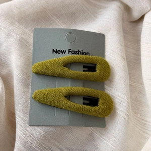 Détail de barrettes à cheveux en velours vert olive sur carte de présentation
