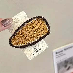 Macro detail of yellow crochet hair clip with brown edges on display card