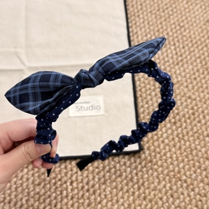 Detail of blue plaid and polka dot headband showing fabric texture and bow design