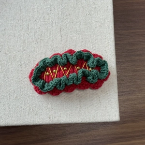 Close-up of handmade crochet Christmas hair clip with red and green knit patterns