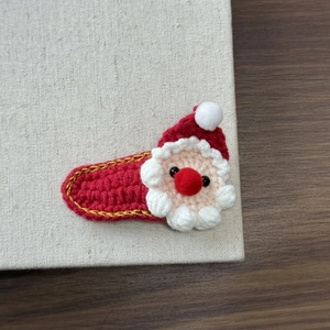 Close-up of handmade crochet Santa Claus hair clip with festive red and white wool details