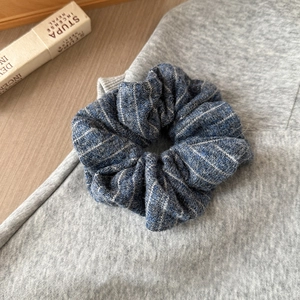 Detail shot of blue and gray striped knitted fabric scrunchie for winter hair accessory
