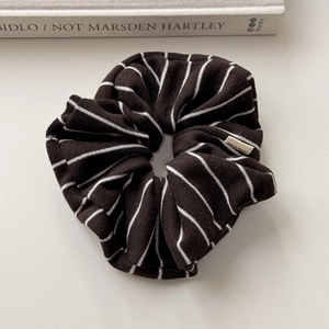 Detailed close-up of knit scrunchie with brown stripes and a Hand Made woven label
