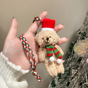 Detailansicht eines Plüsch-Weihnachtsbären-Anhängers mit rotem Hut und Strickschal
