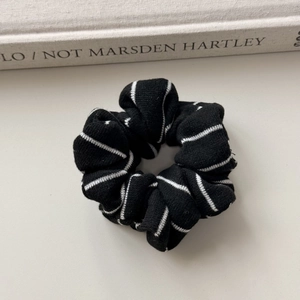 Close-up of black and white striped knit scrunchie with soft ribbed cotton texture