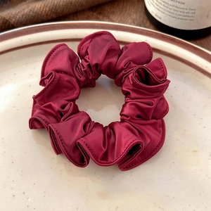 Close-up of burgundy satin scrunchie with silk luster on a vintage ceramic plate