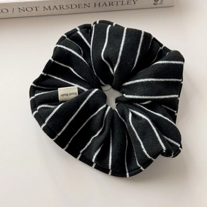 Close-up of black and white striped knitted scrunchie with handmade fabric label