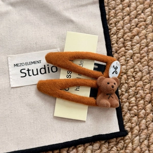 Detail of two orange felt hair clips with cute flocking bear and seashell pattern bow