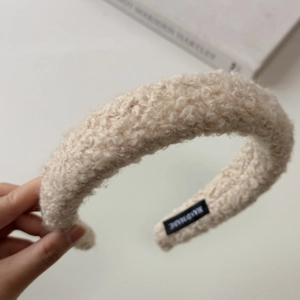 Detail of plush beige faux shearling headband with handmade label and soft fuzzy texture