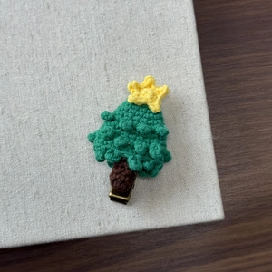 Close-up of handmade knitted Christmas tree hair clip with festive crochet texture details