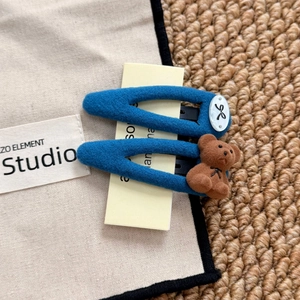 Close-up of blue flocked flower hair clips with brown bear and bow-knot details